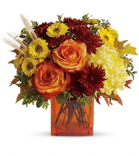 Autumn bouquet of orange roses, yellow daisies, and red mums in an amber vase.