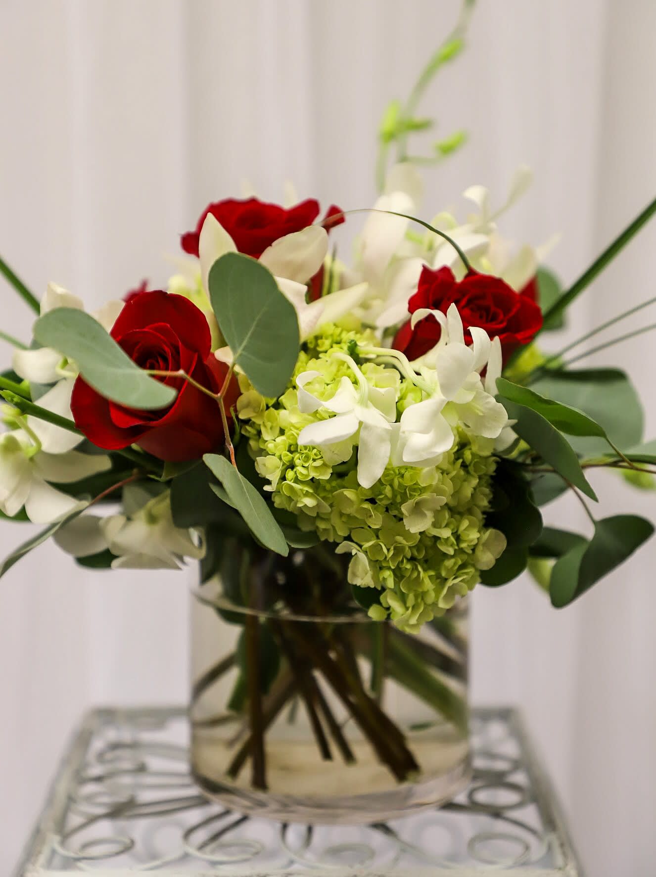 Red roses and white flowers arranged in a clear glass vase
