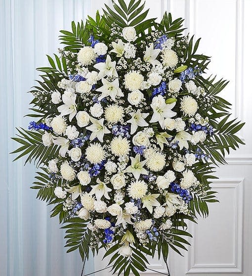 Large white and blue funeral spray with lilies and roses