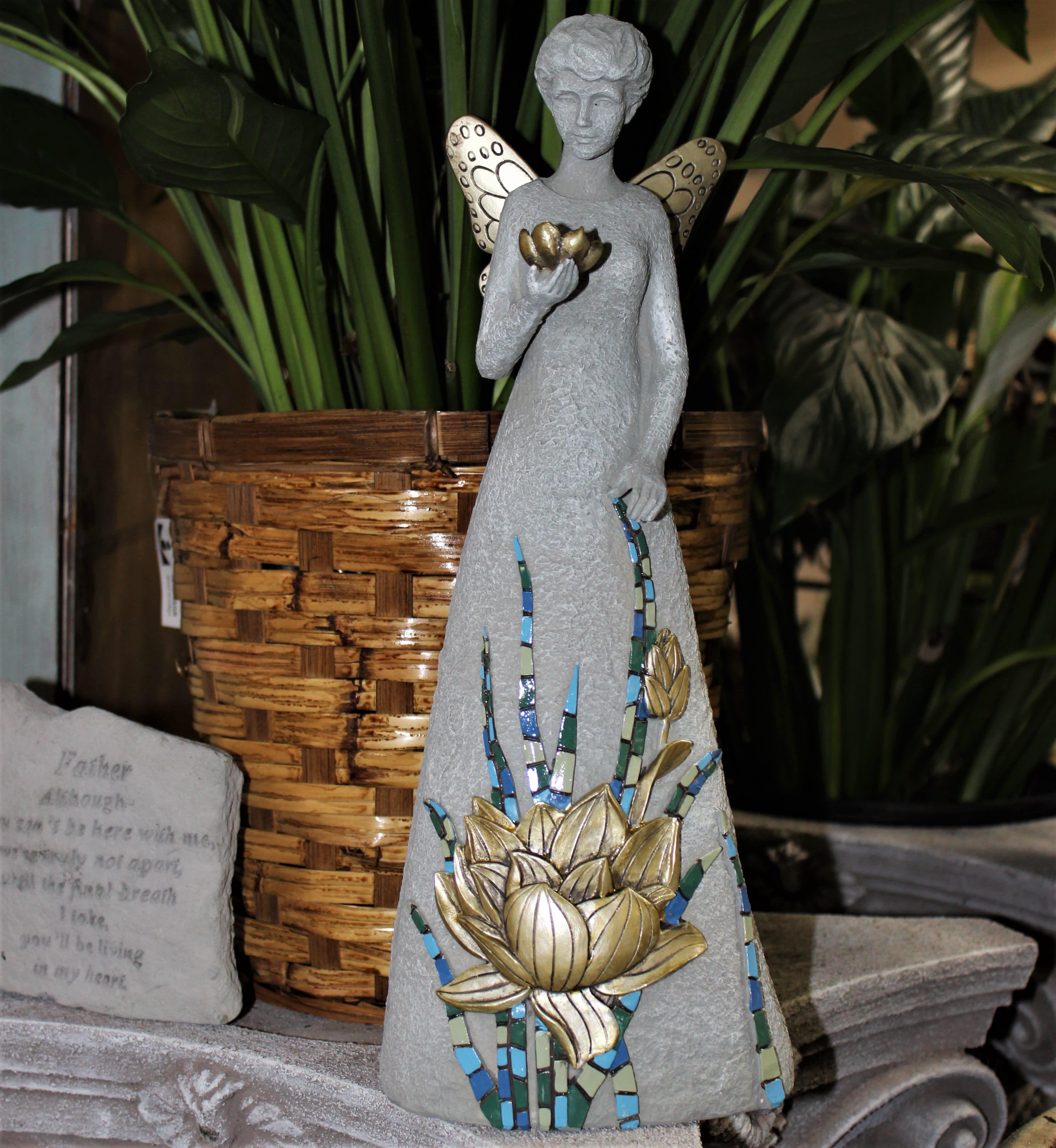 Decorative angel statue with mosaic flower detail beside a woven planter