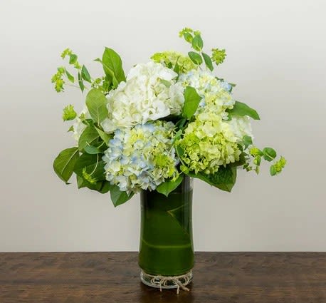 Hydrangea arrangement in a tall green glass vase