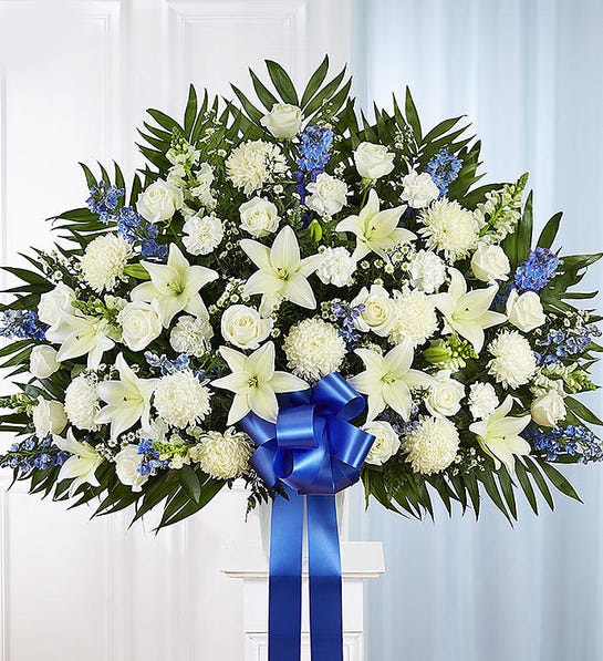 Large white floral standing spray with a blue ribbon bow