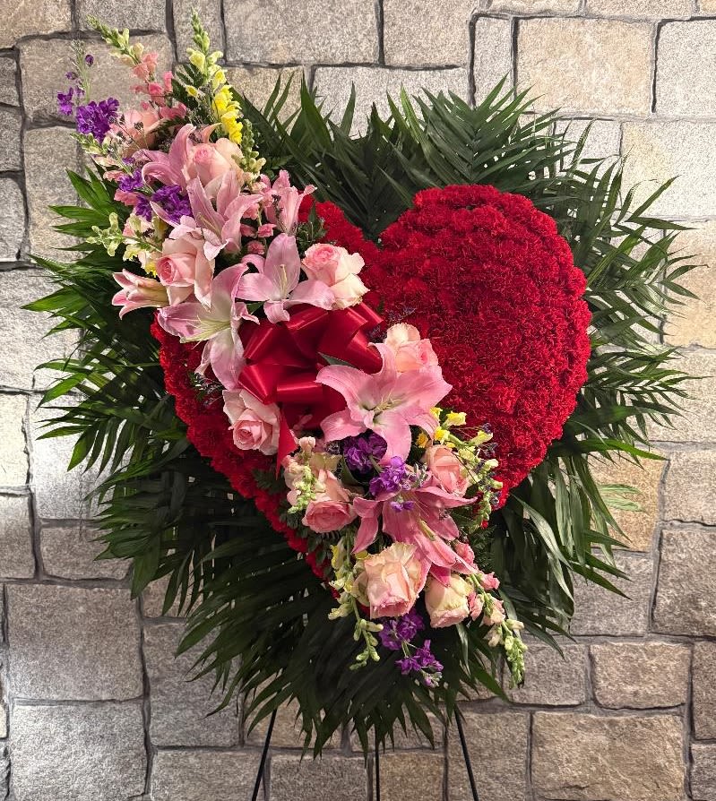 Heart-shaped floral spray with pink lilies and roses on a stand