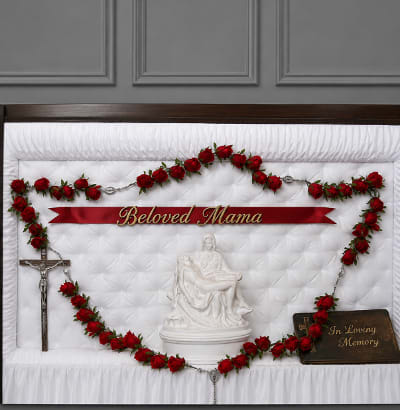 Red rose funeral casket spray with memorial ribbon and crucifix