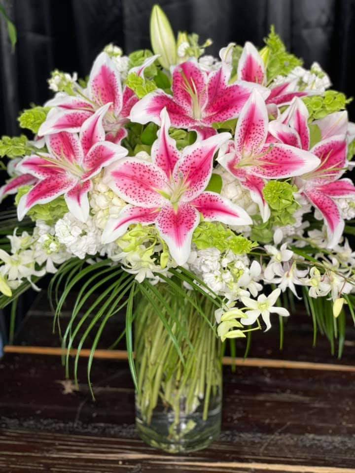 Pink stargazer lilies and white flowers in a glass vase