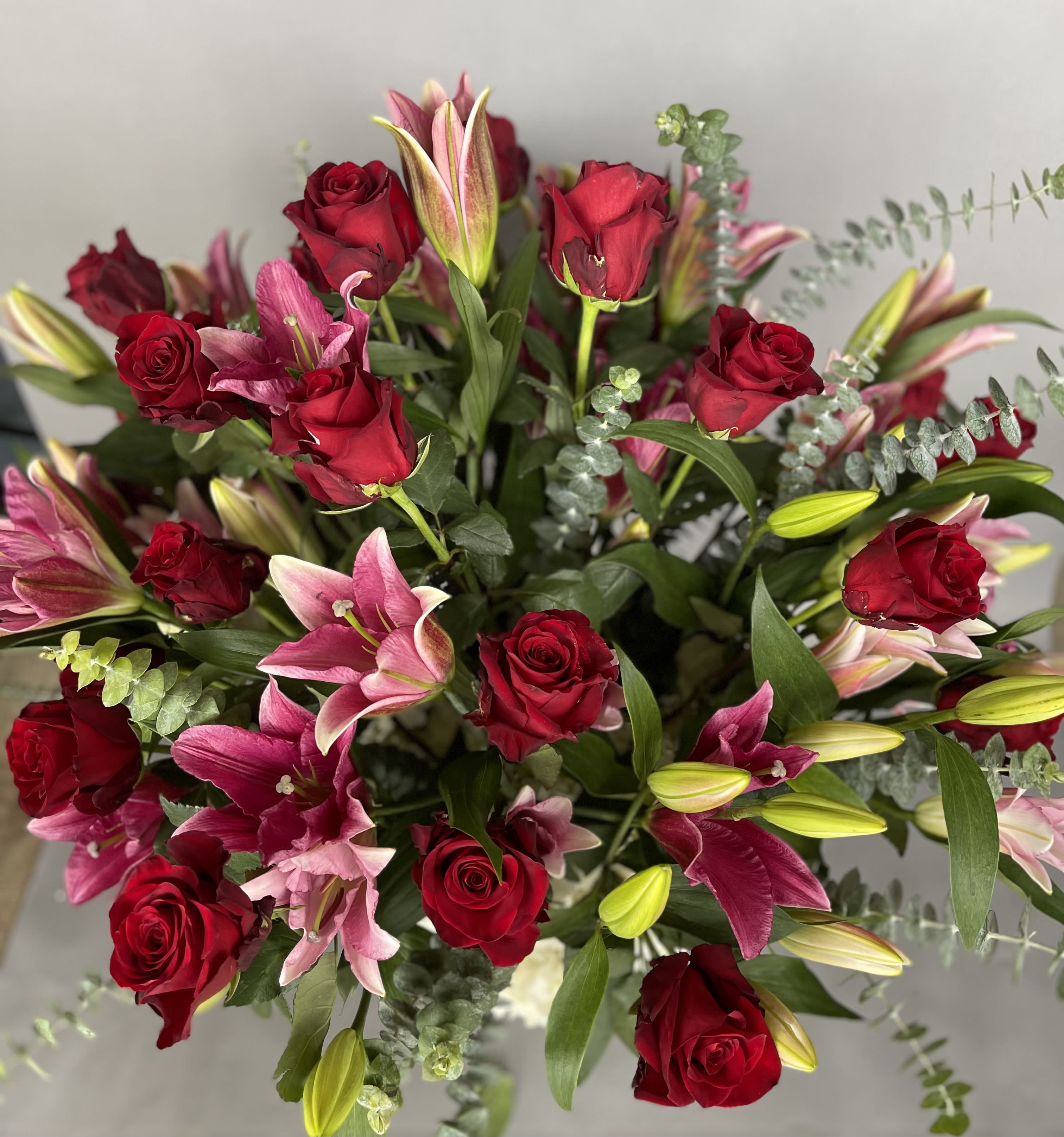 Bouquet of red roses and pink lilies with greenery