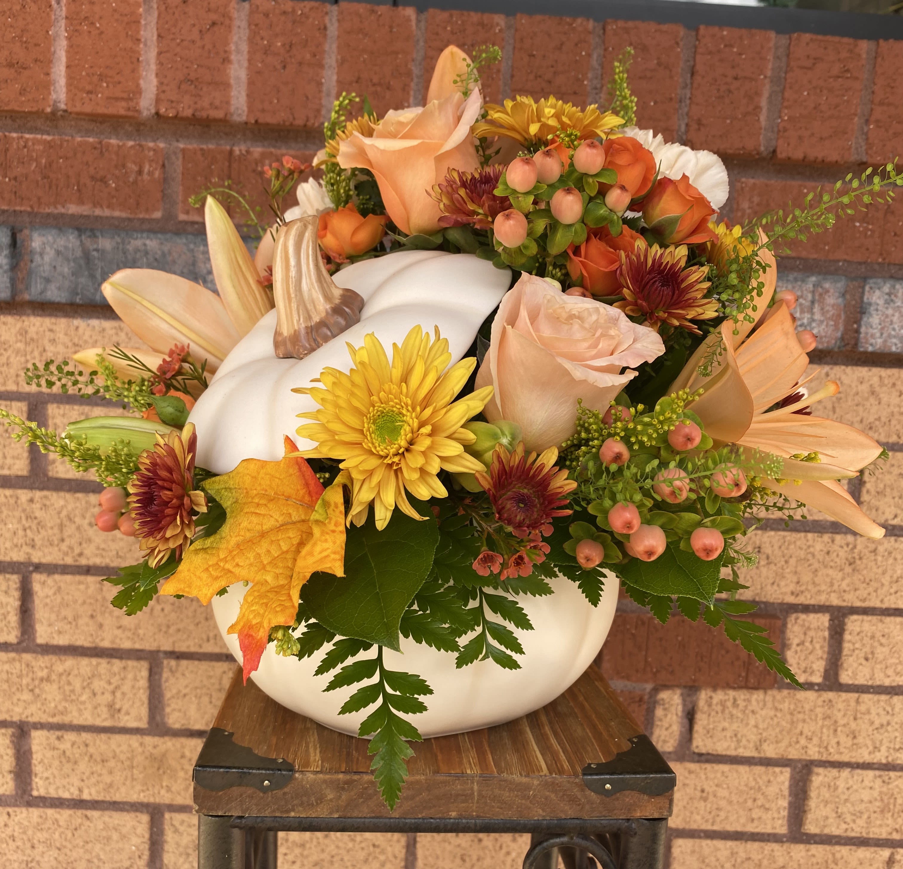 Fall floral arrangement in a white pumpkin container with roses and mums