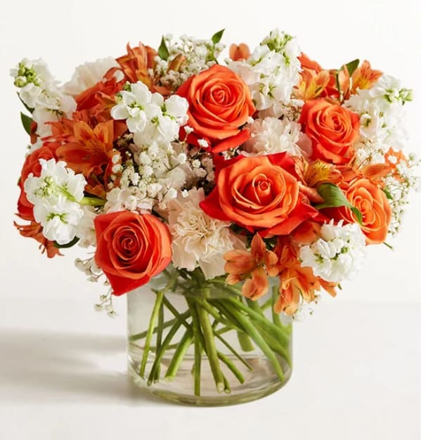 Bouquet of orange roses and white flowers in a clear glass vase