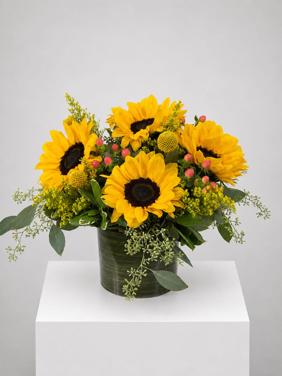 Sunflower arrangement in a dark green cylindrical vase with yellow accents