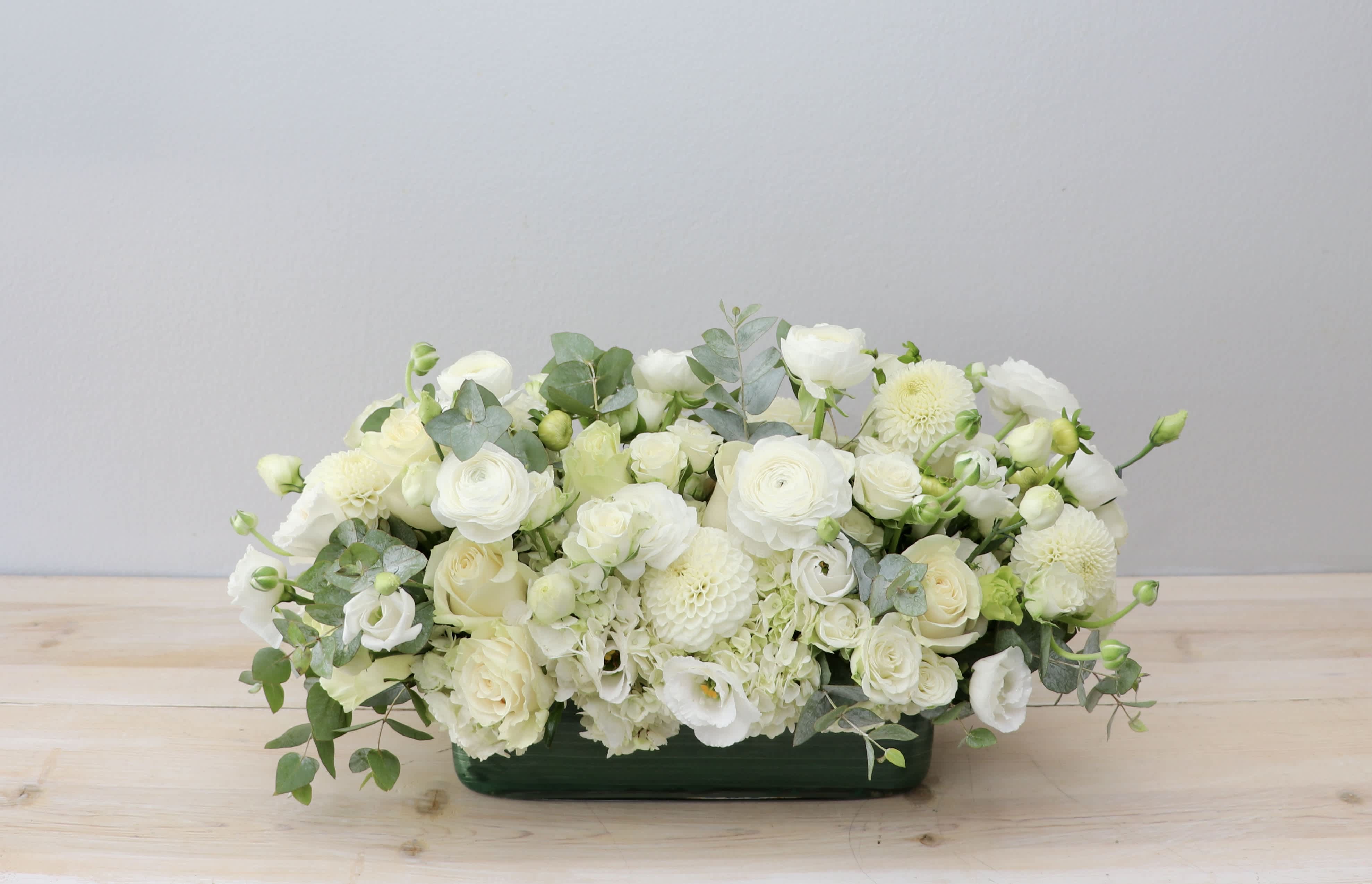 White floral arrangement in a low green container