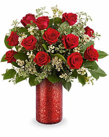 Red roses arranged in a red vase with white filler flowers
