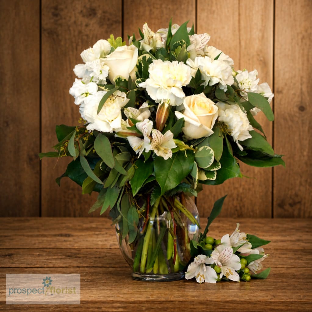 White floral arrangement in a clear glass vase with a matching small cluster beside it