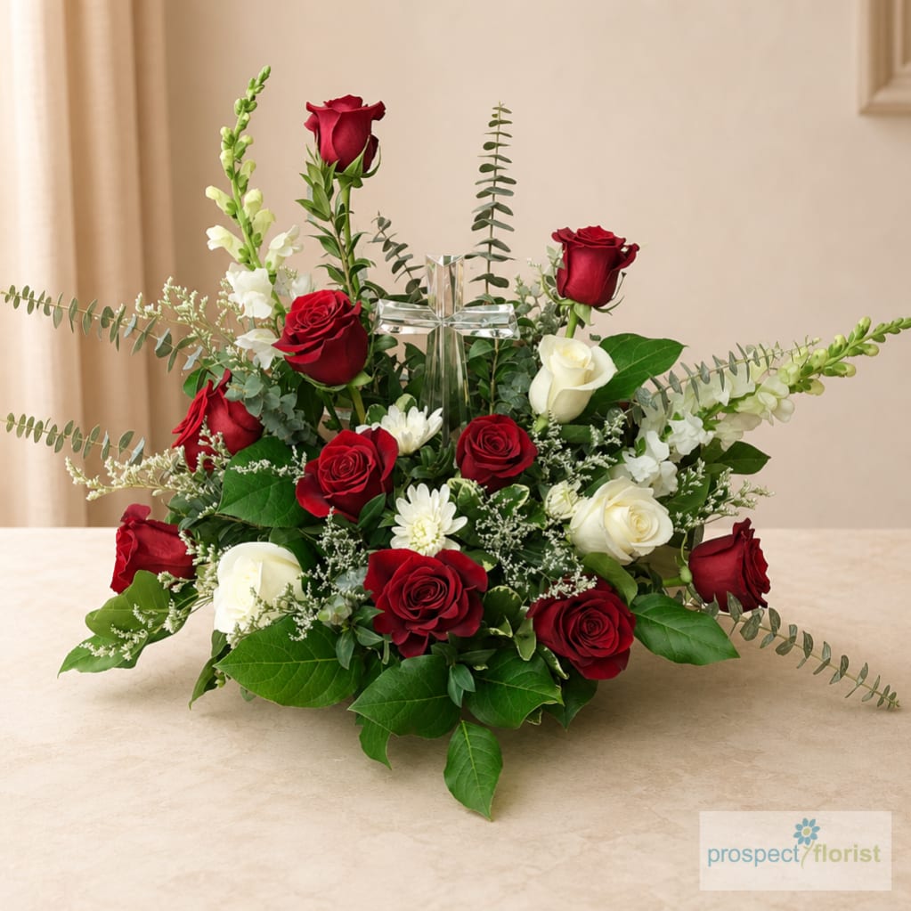 Red and white rose arrangement with a clear glass cross centerpiece