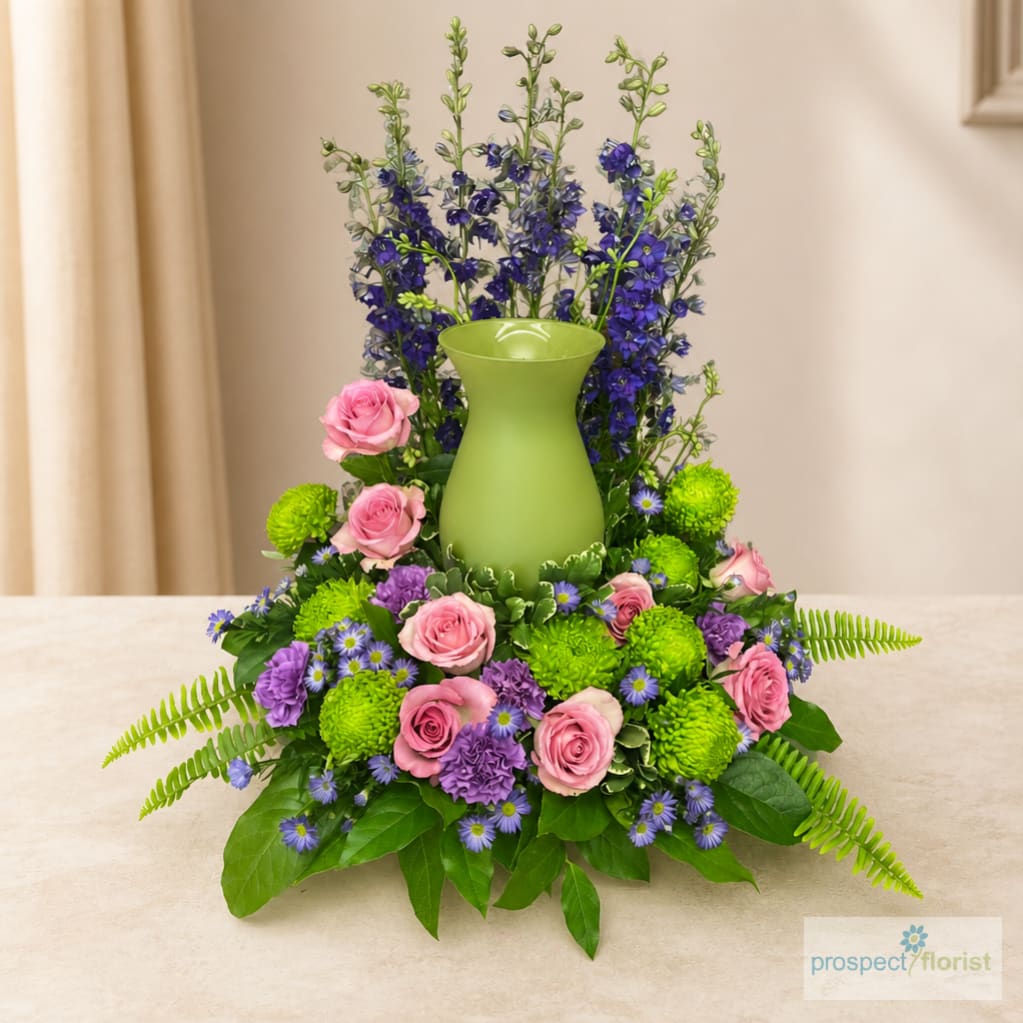 Pink roses and purple flowers arranged around a green vase