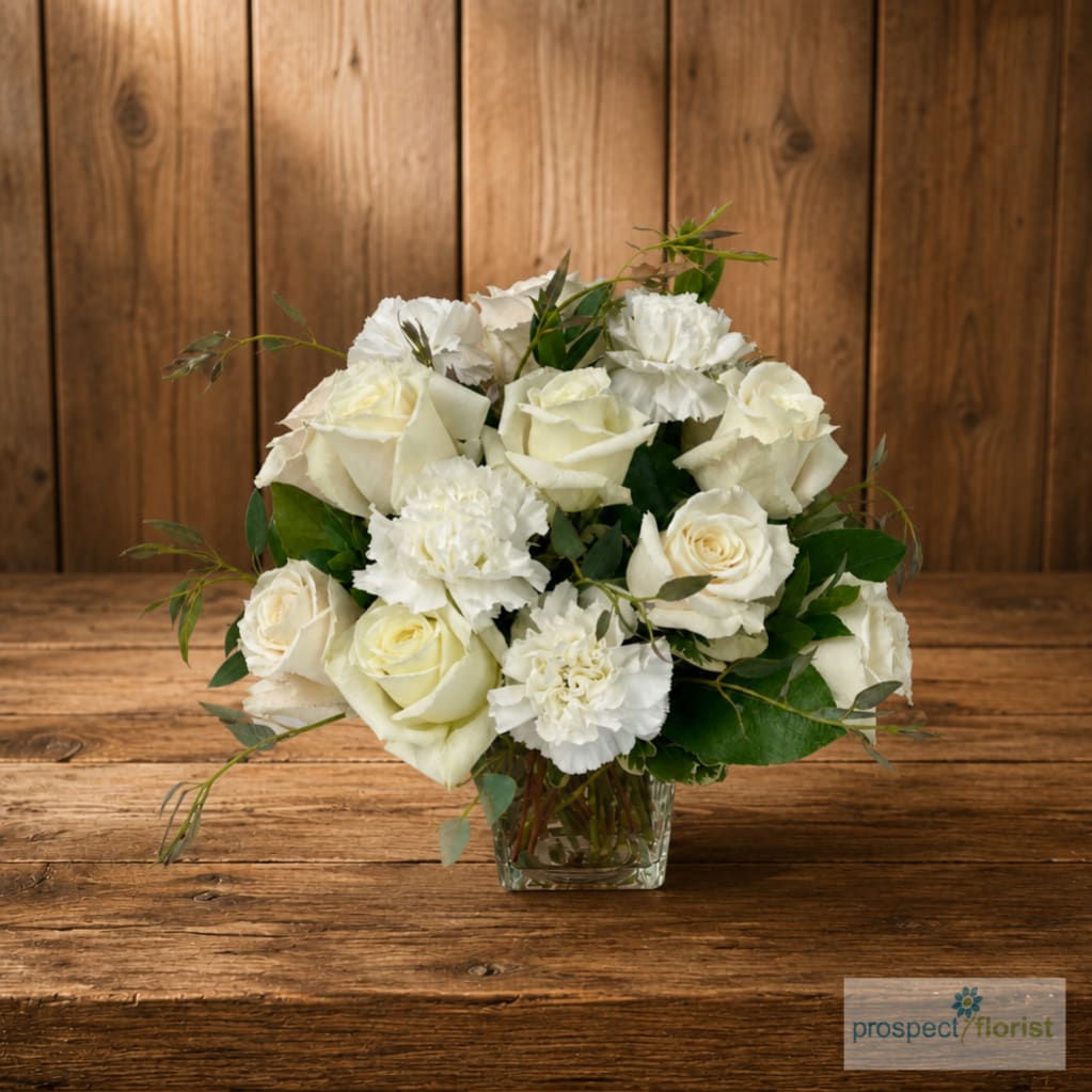 White rose and carnation bouquet in a clear glass vase