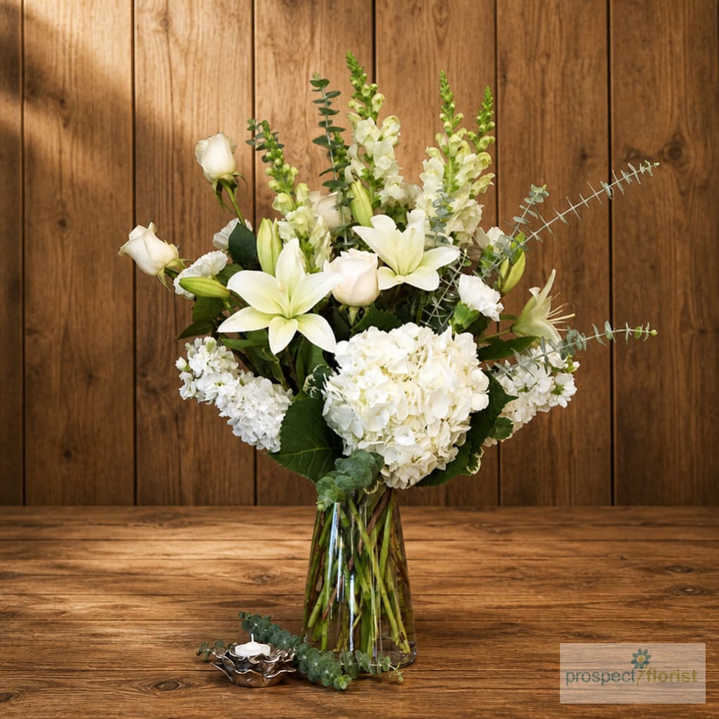 White lilies and hydrangeas in a clear glass vase