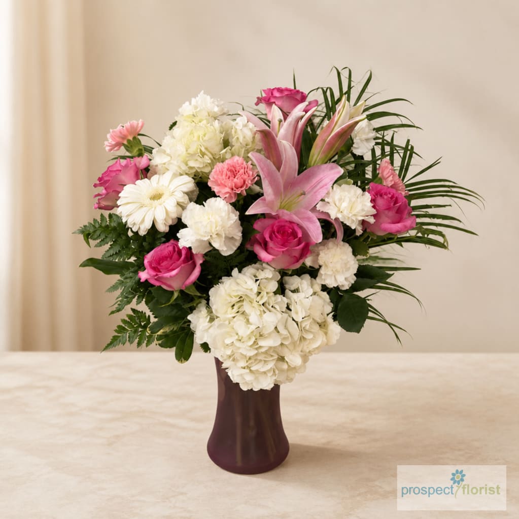 Pink and white mixed flower arrangement in a dark vase