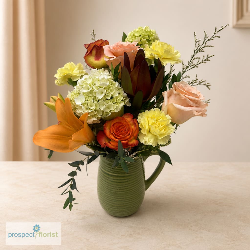 Mixed bouquet of roses, lilies, hydrangeas, and carnations in a green vase