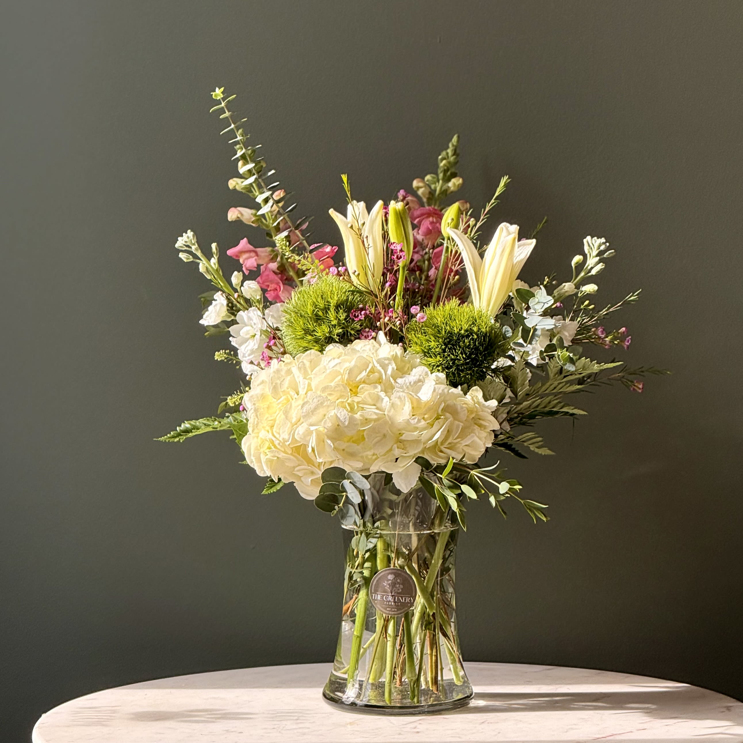 Simply Sweet - Beautiful floral arrangement in a clear vase with lilies, hydrangeas, snapdragon, green trick, and eucalyptus. As a local florist in Charleston South Carolina, everything is made fresh by us here at our flower shop Downtown Charleston.