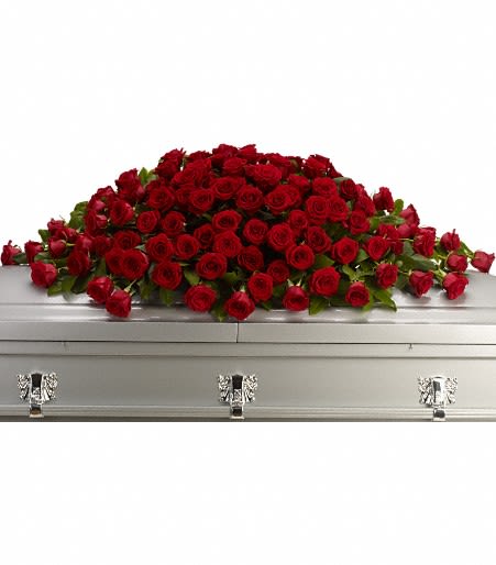 Large spray of red roses arranged atop a silver casket