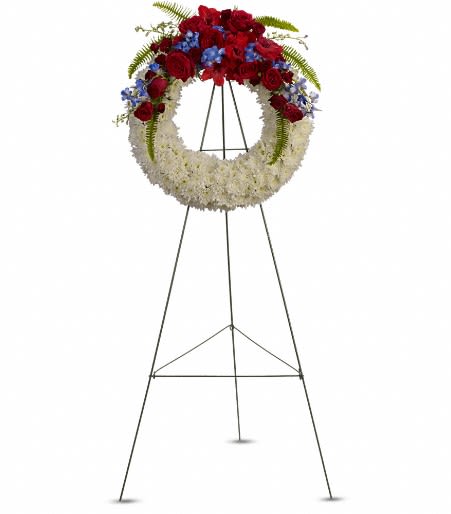Patriotic red, white, and blue floral wreath on a tall metal easel stand