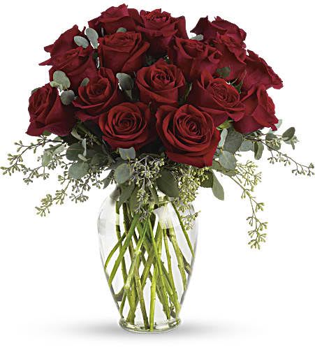 Arrangement of long-stem red roses with filler in a clear glass vase