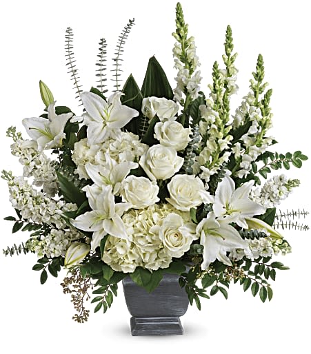 Large all-white arrangement of lilies, roses, hydrangeas and snapdragons in a gray urn vase