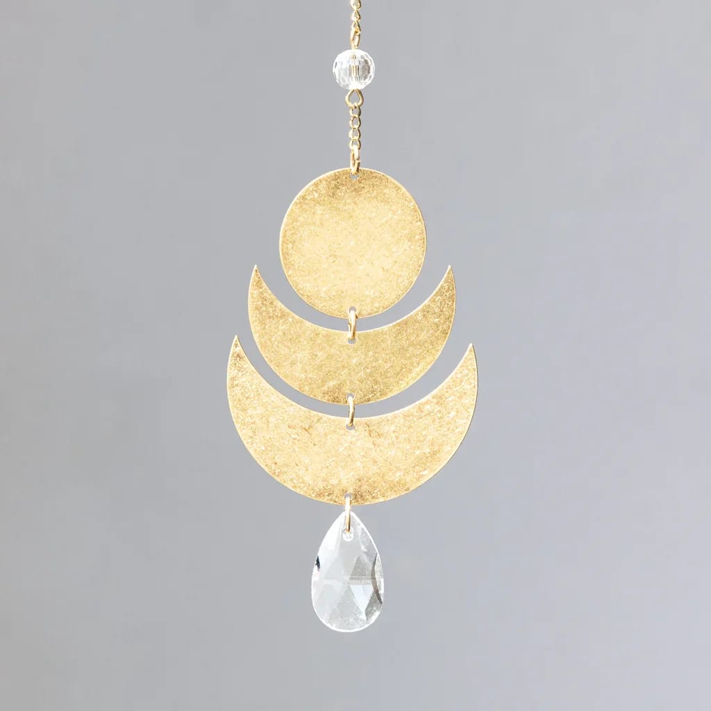 Gold hanging ornament with circular and crescent shapes and a clear teardrop crystal