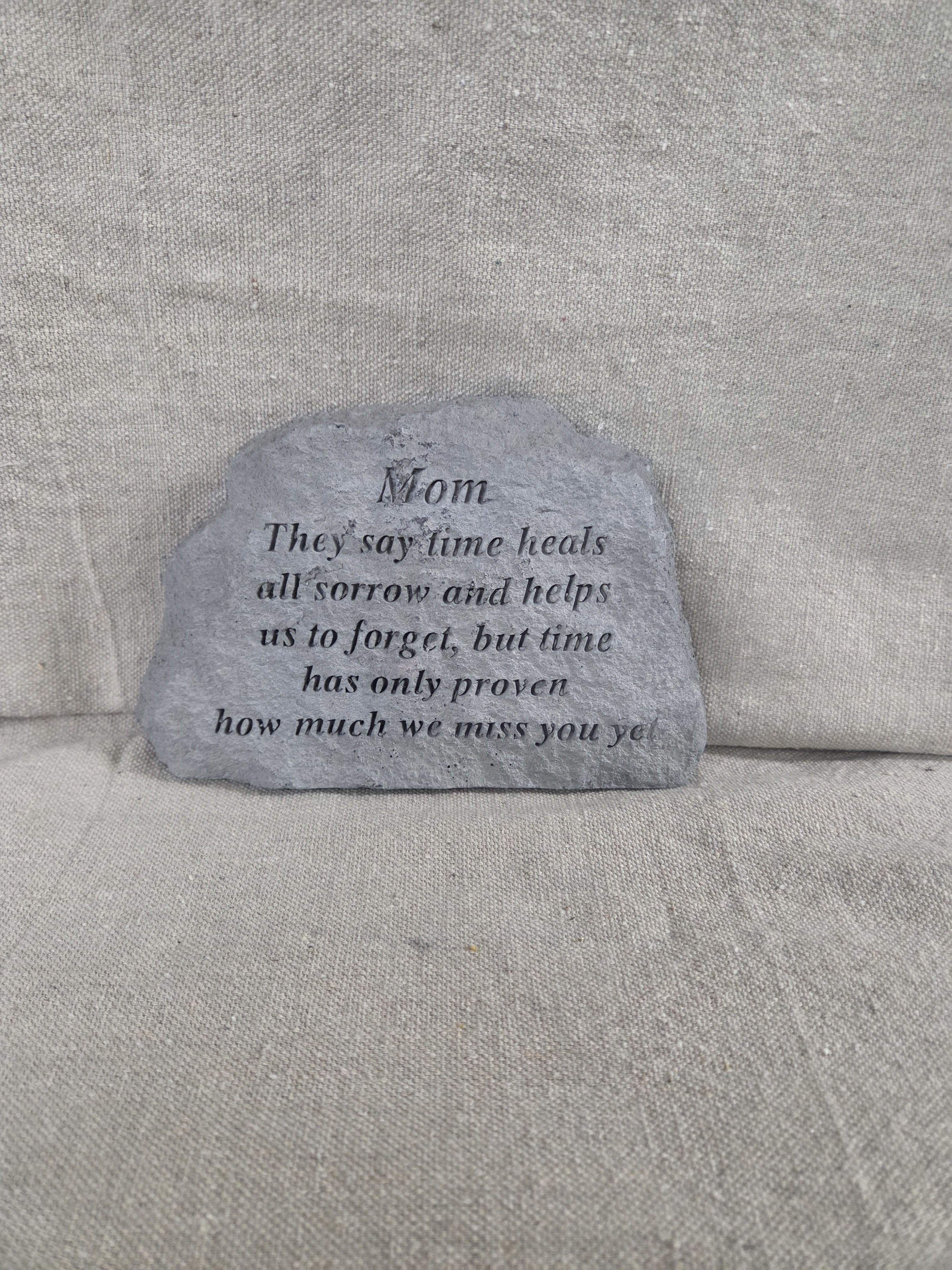 Gray memorial stone engraved with a Mom remembrance verse on a neutral fabric background.