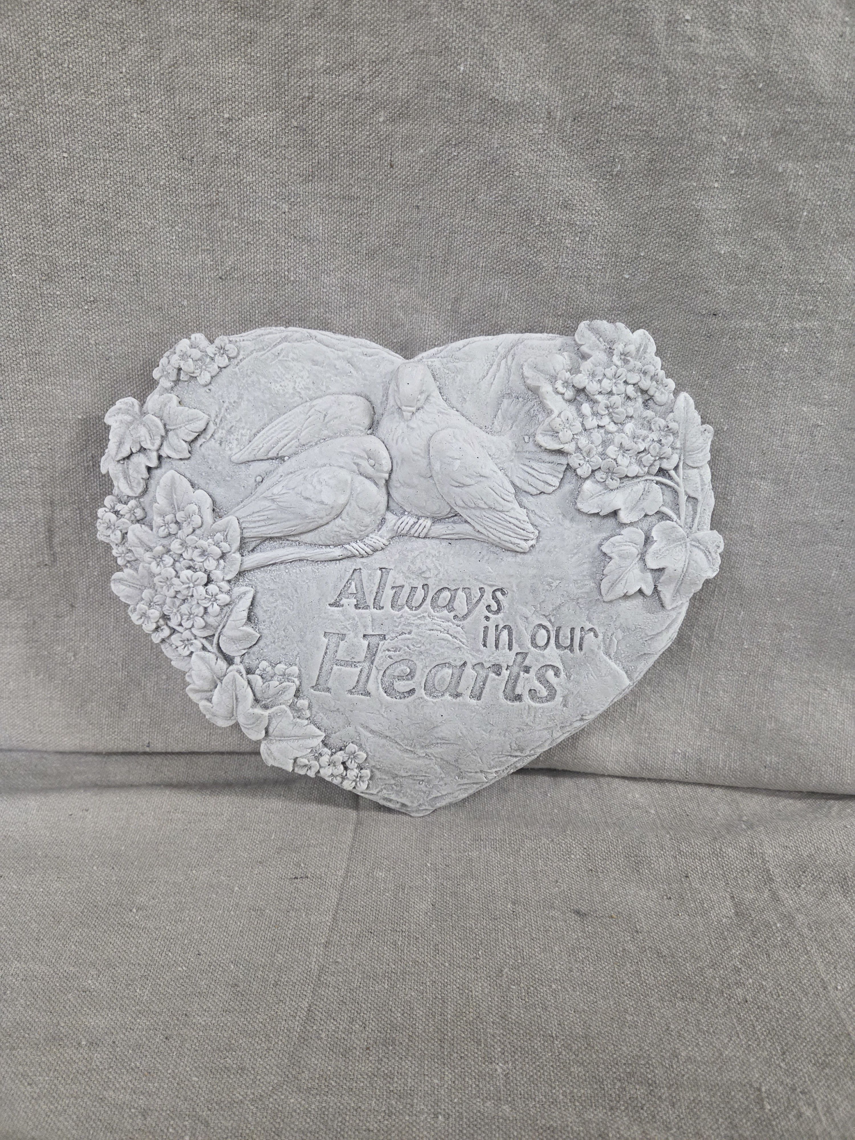 Heart-shaped stone memorial plaque with doves, carved flowers, and the words Always in our Hearts.