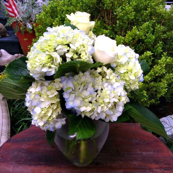 White hydrangeas and roses arranged in a metallic vase