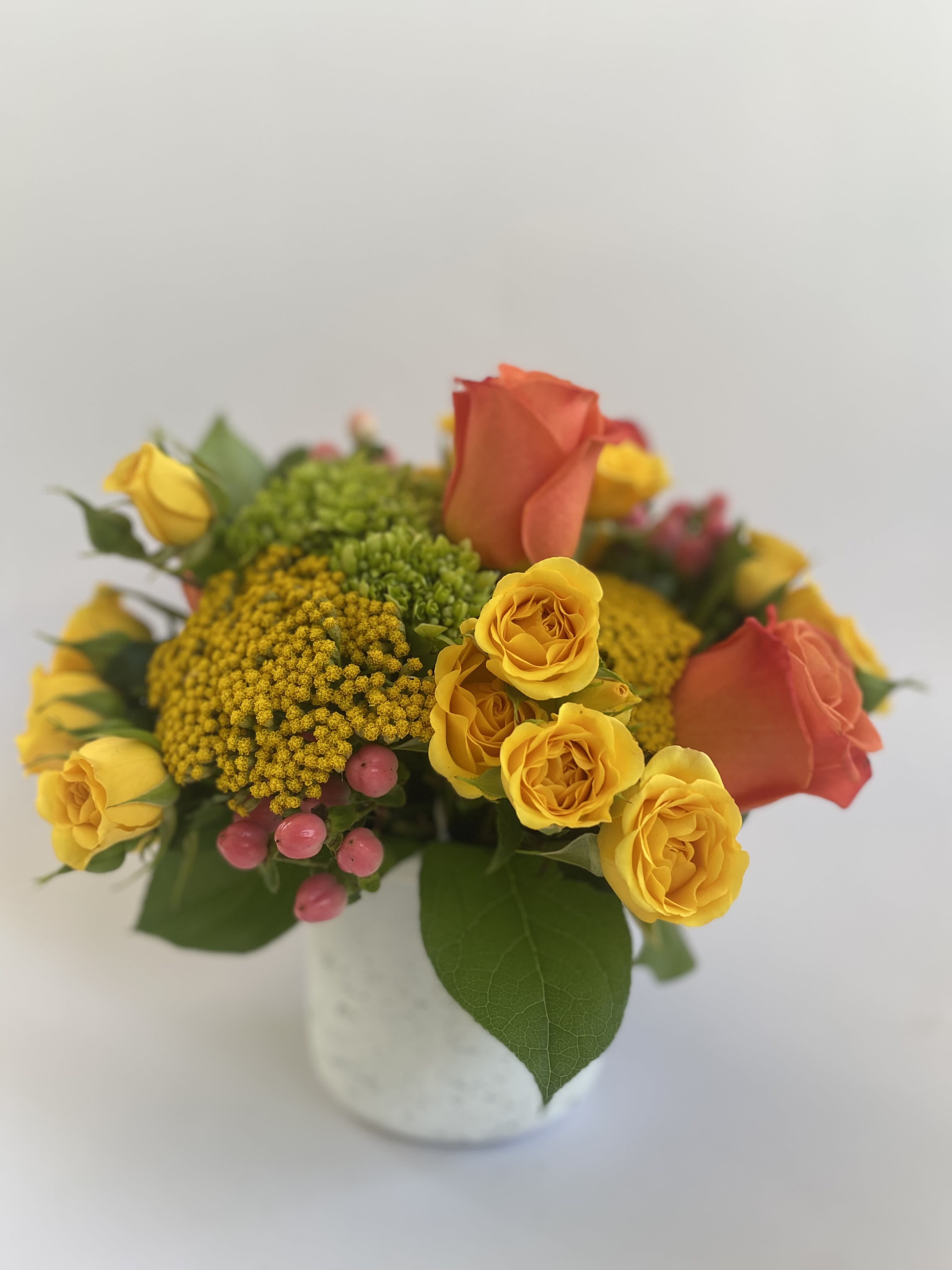 Yellow and coral roses in a white vase