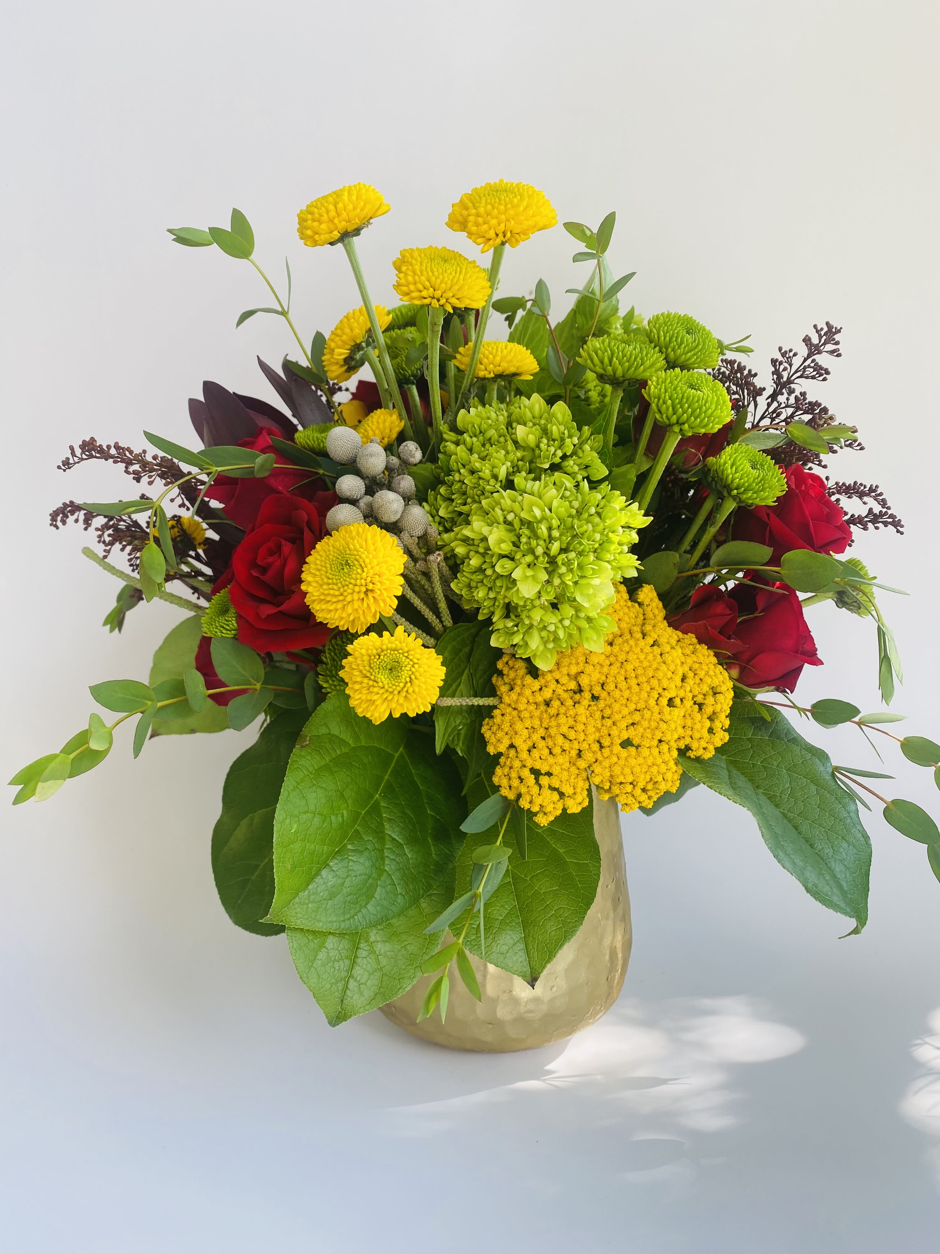 Mixed bouquet of red roses and yellow chrysanthemums in a gold vase