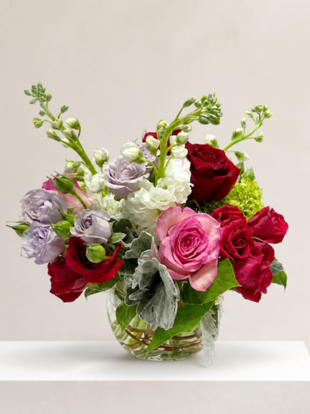 Mixed roses and white blooms arranged in a clear glass vase