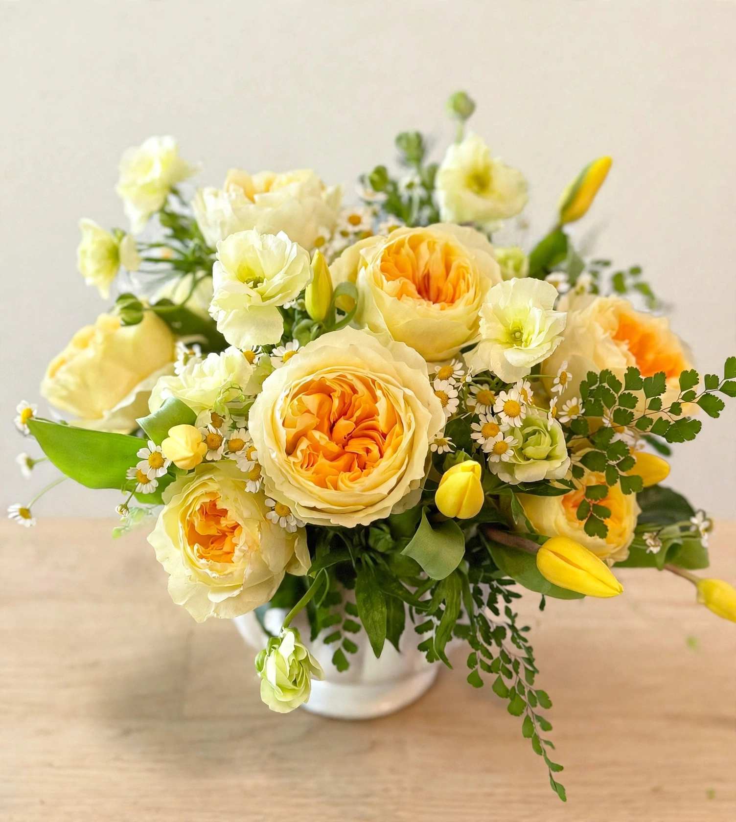 Yellow and cream roses arranged in a white vase