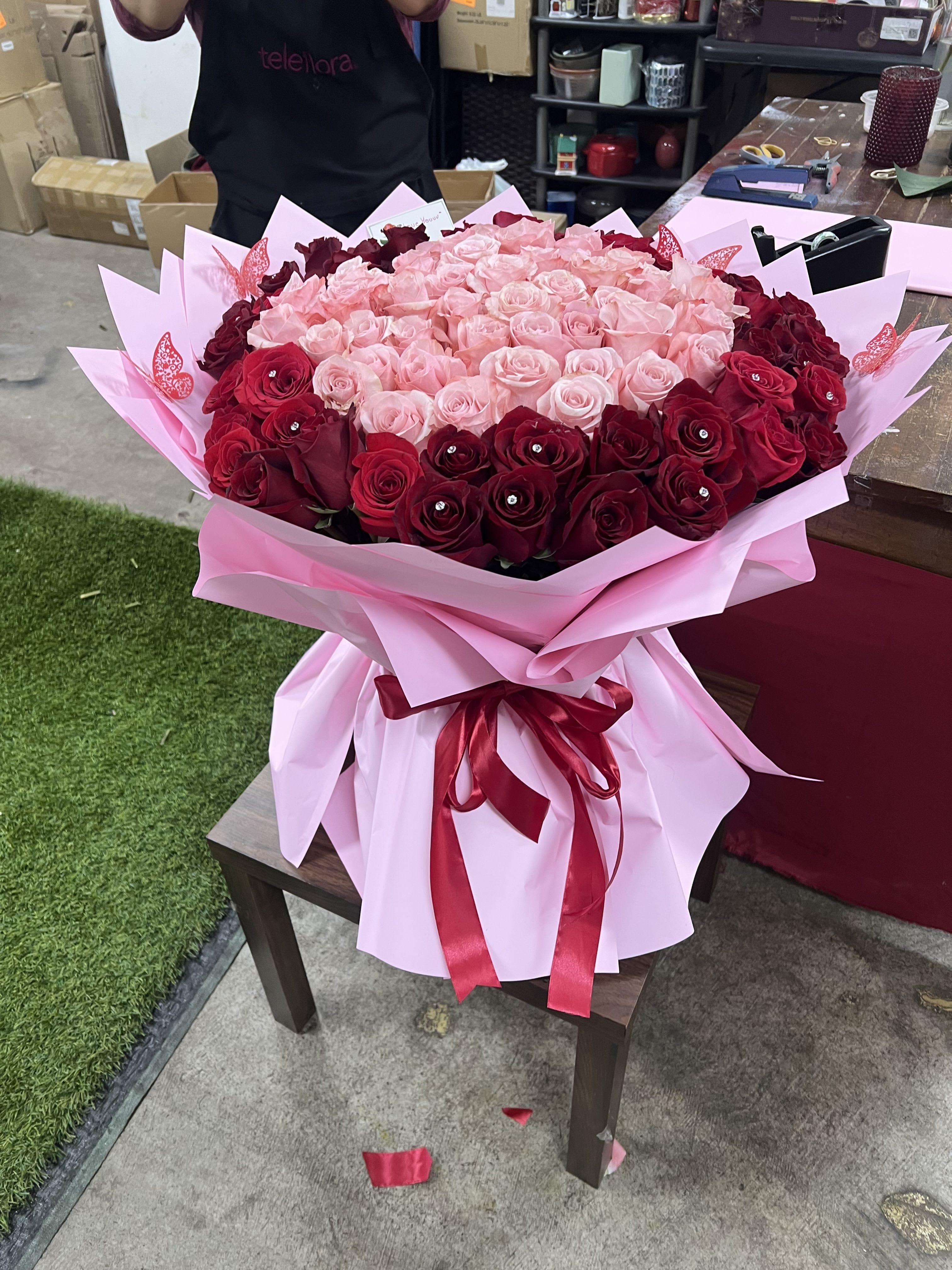 Large bouquet of pink and red roses wrapped in pink paper with a ribbon
