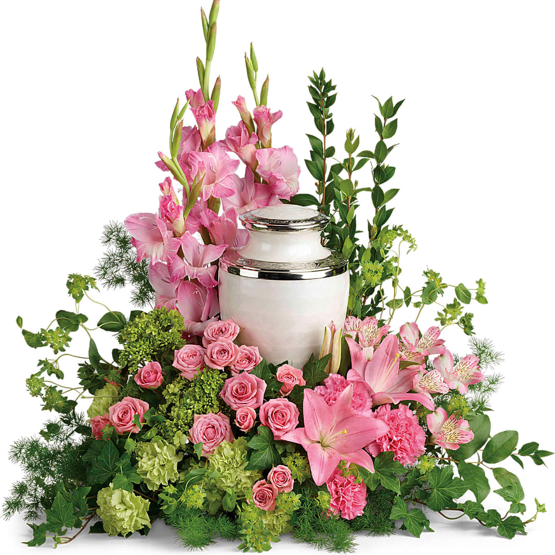 Pink flowers arranged around a white urn with silver trim