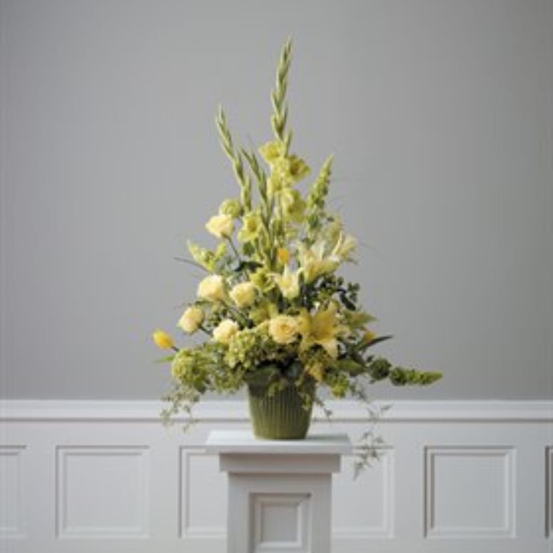 Tall yellow floral arrangement in a green vase on a pedestal