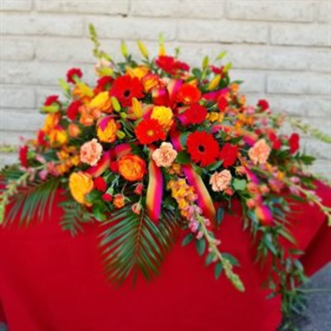 Bright mixed flower arrangement with red, orange, and yellow blooms in a low display