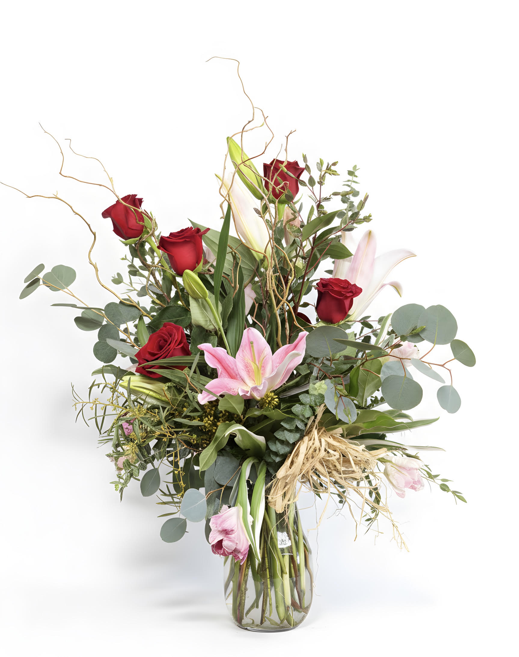Red roses and pink lilies in a glass vase with greenery