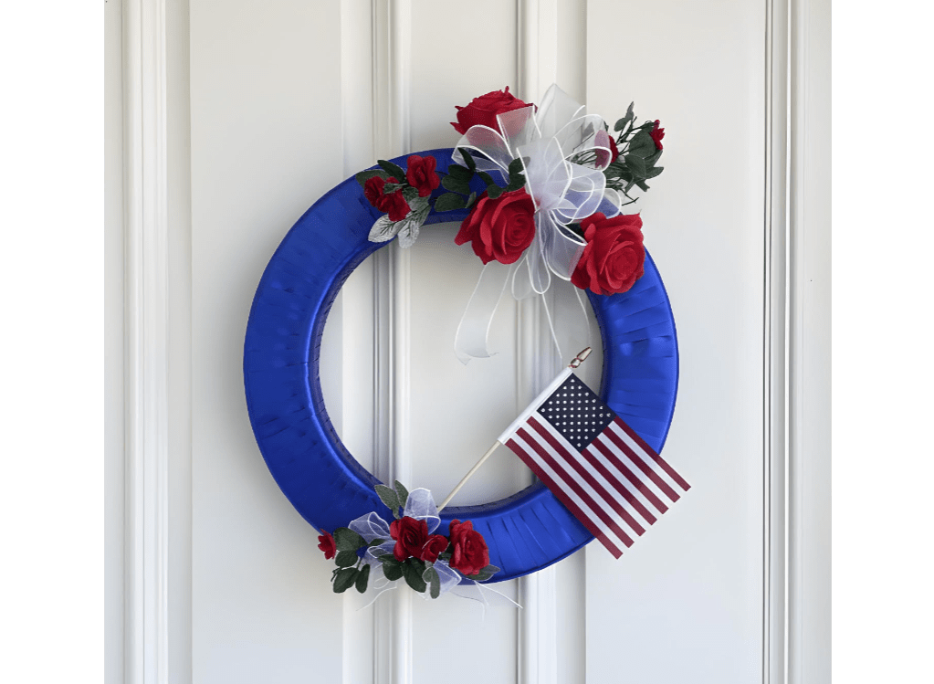 Blue wreath with red roses, white ribbon, and a small American flag