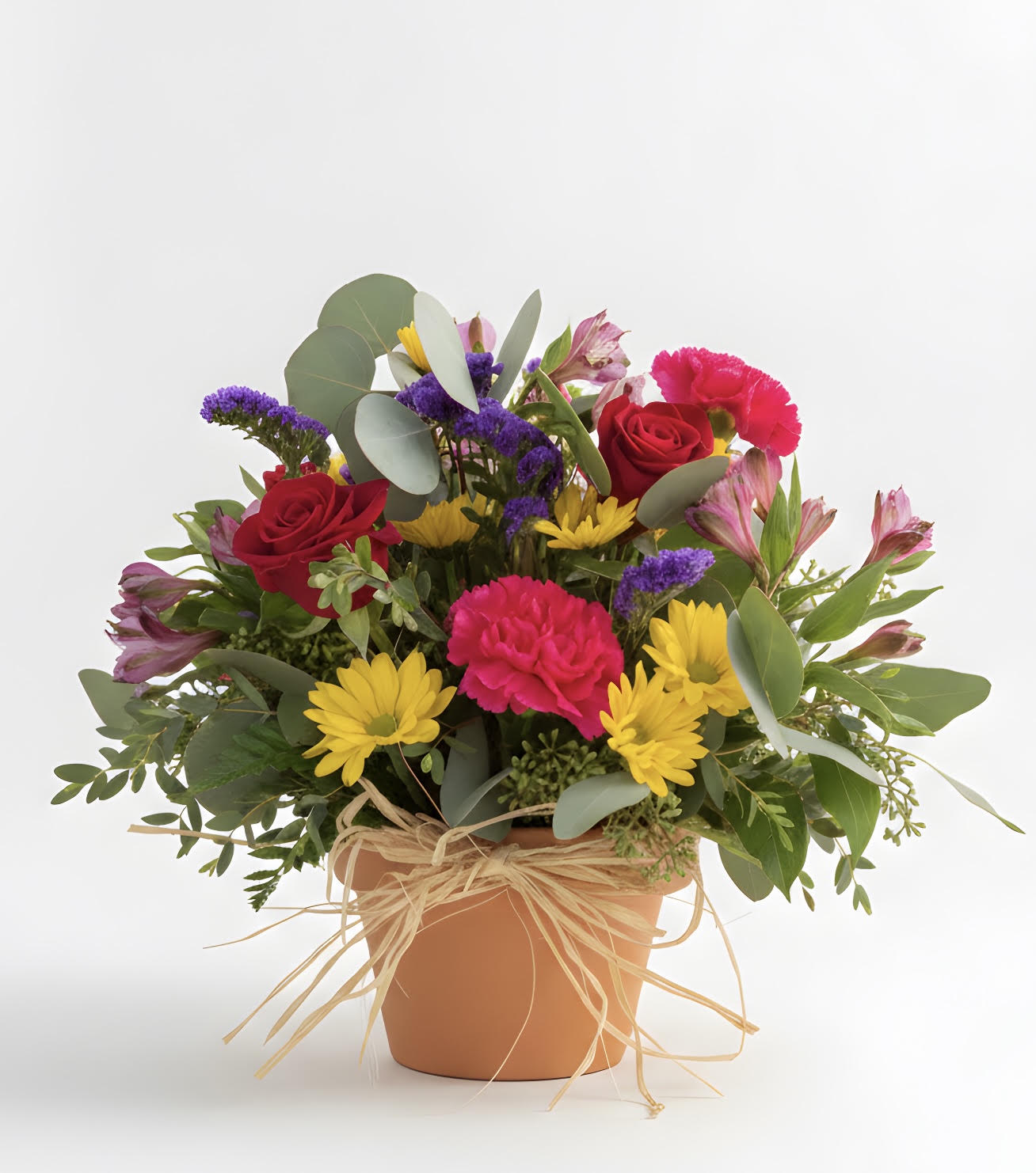 Mixed bouquet of red roses, yellow daisies, and pink flowers in a terracotta pot