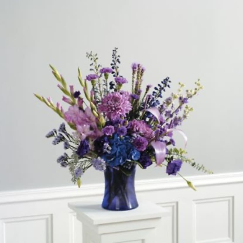 Purple and blue flower arrangement in a dark blue vase