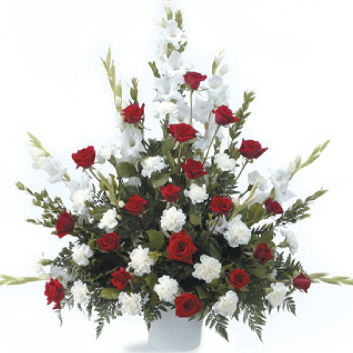 Red roses and white flowers arranged in a tall white vase