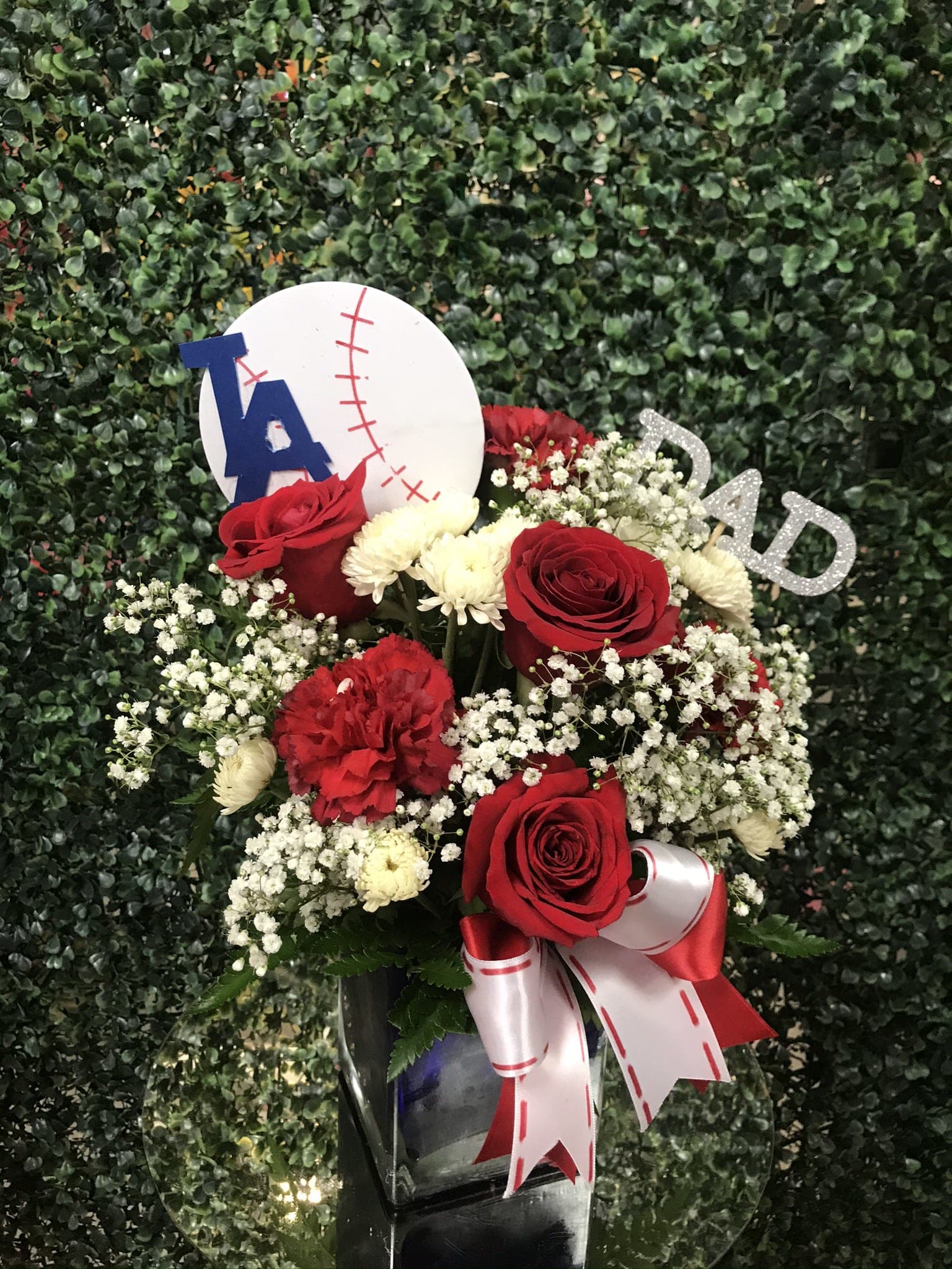 Red roses and white flowers in a vase with baseball-themed decorations
