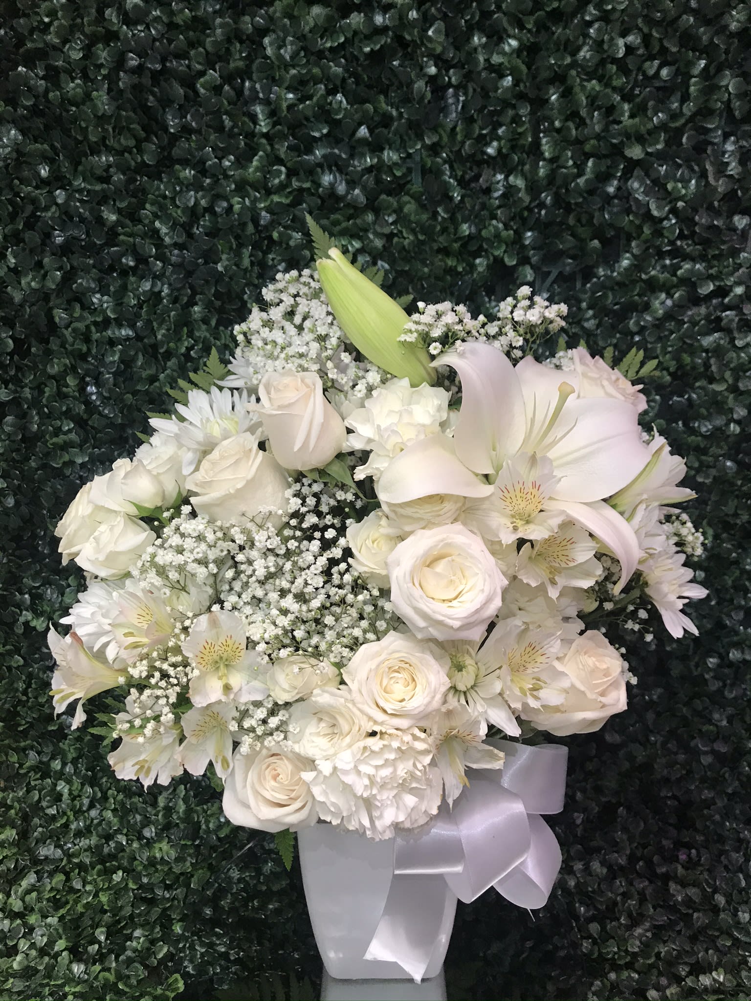 White rose and lily bouquet with baby's breath in a white vase