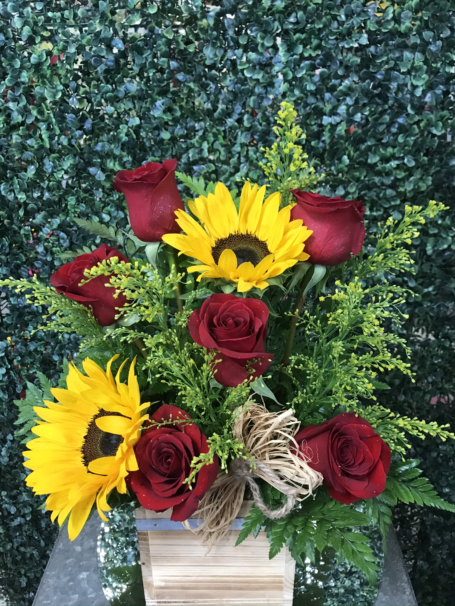 Red roses and yellow sunflowers in a wooden box