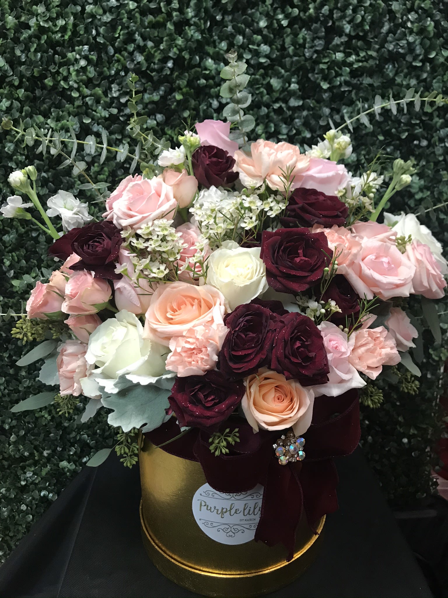 Bouquet of pink, burgundy, and white roses in a gold hatbox with ribbon