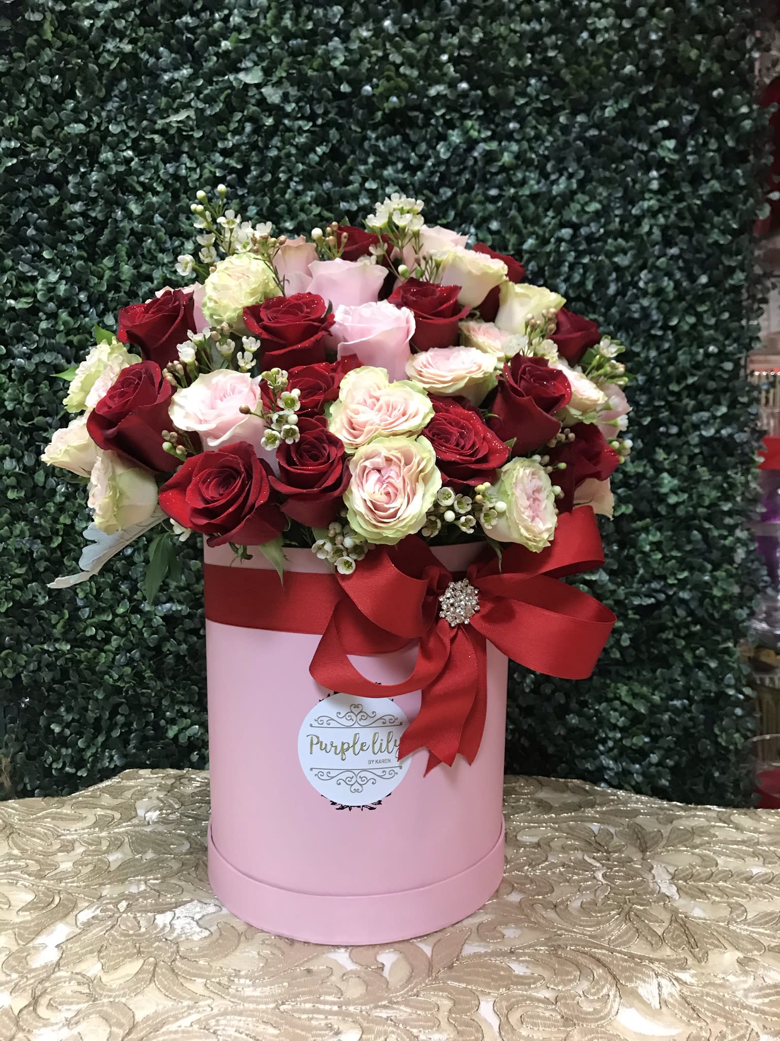 Pink hatbox arrangement of red and blush roses with a red ribbon