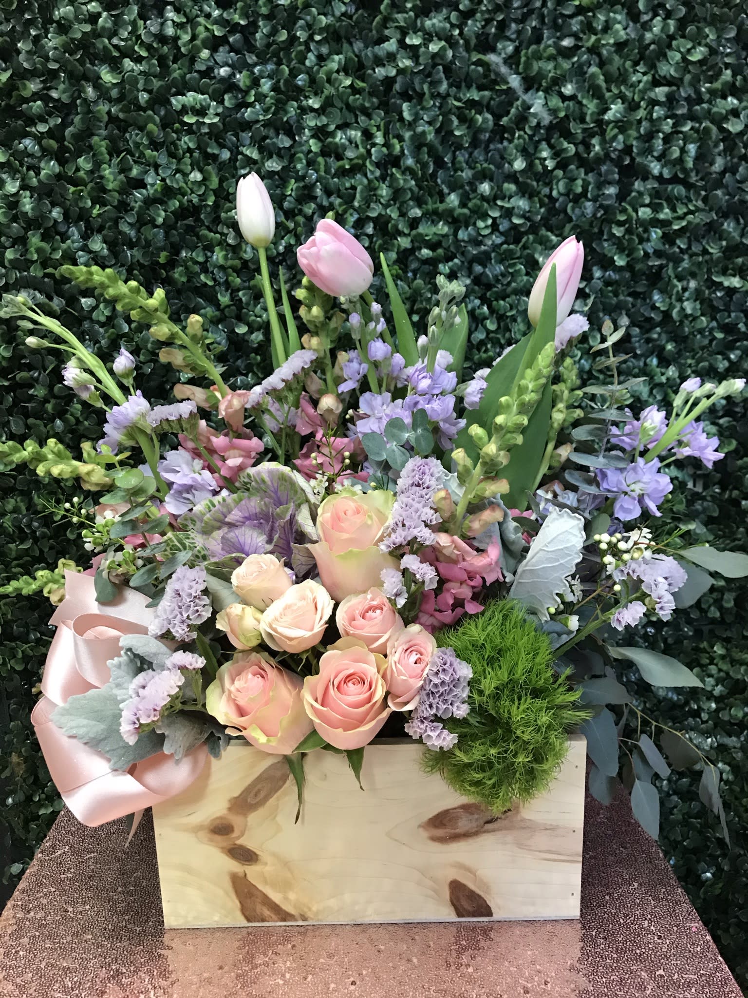 Pastel bouquet with pink roses and tulips in a wooden box